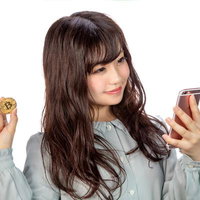スマートフォンでビットコインをトレードする女性の写真