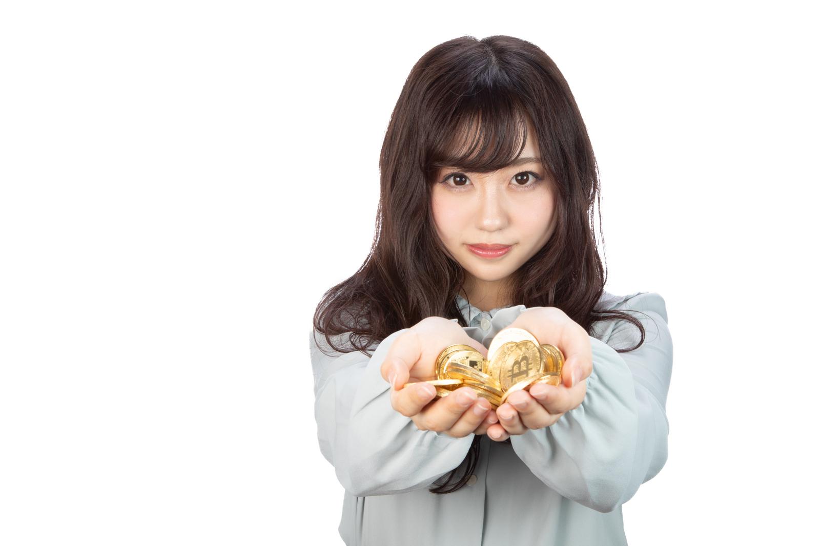 両手を前に出してビットコインを持つ笑顔の女性［モデル：河村友歌］