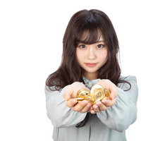 両手いっぱいに広げたビットコインを持つ女性の写真