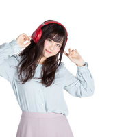 赤いヘッドフォンで音楽を聞きながらリズムに乗る女性の写真