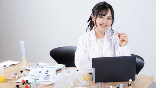 試験管を手に微笑む白衣の女性研究員の写真