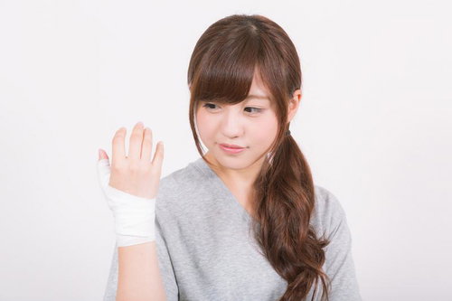 利き手の示指を包帯で固定する女性の手指固定治療