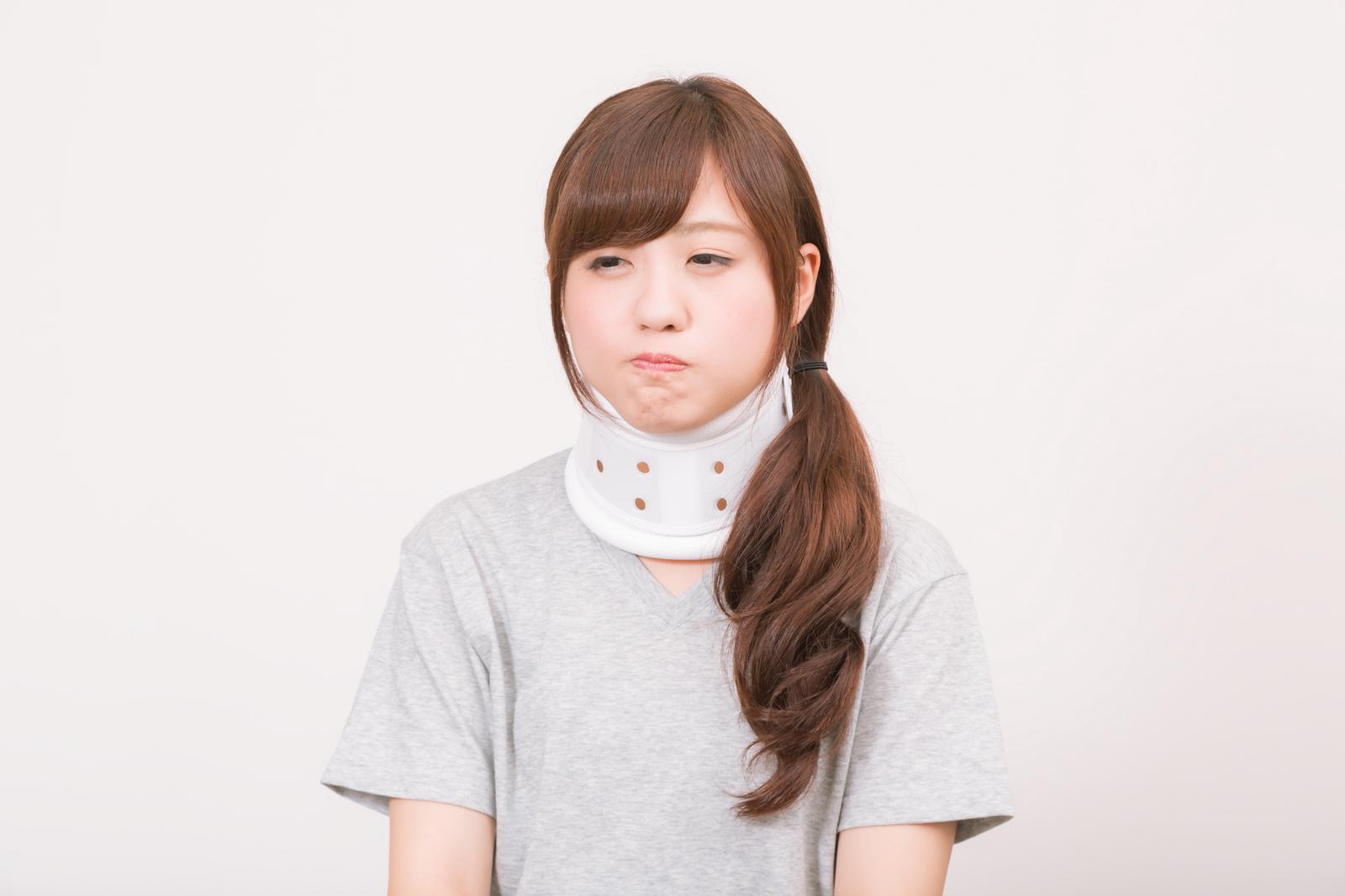 白い頚椎カラーを装着した女性が下向きで立っている［モデル：河村友歌］
