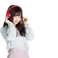 赤いヘッドフォンで目をつぶって音楽に集中する女性の写真