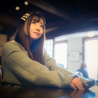 昼間のカフェで窓からの光を浴びながら思案に耽る女性の写真