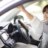 車内のバックミラーを調整する女性ドライバーの写真