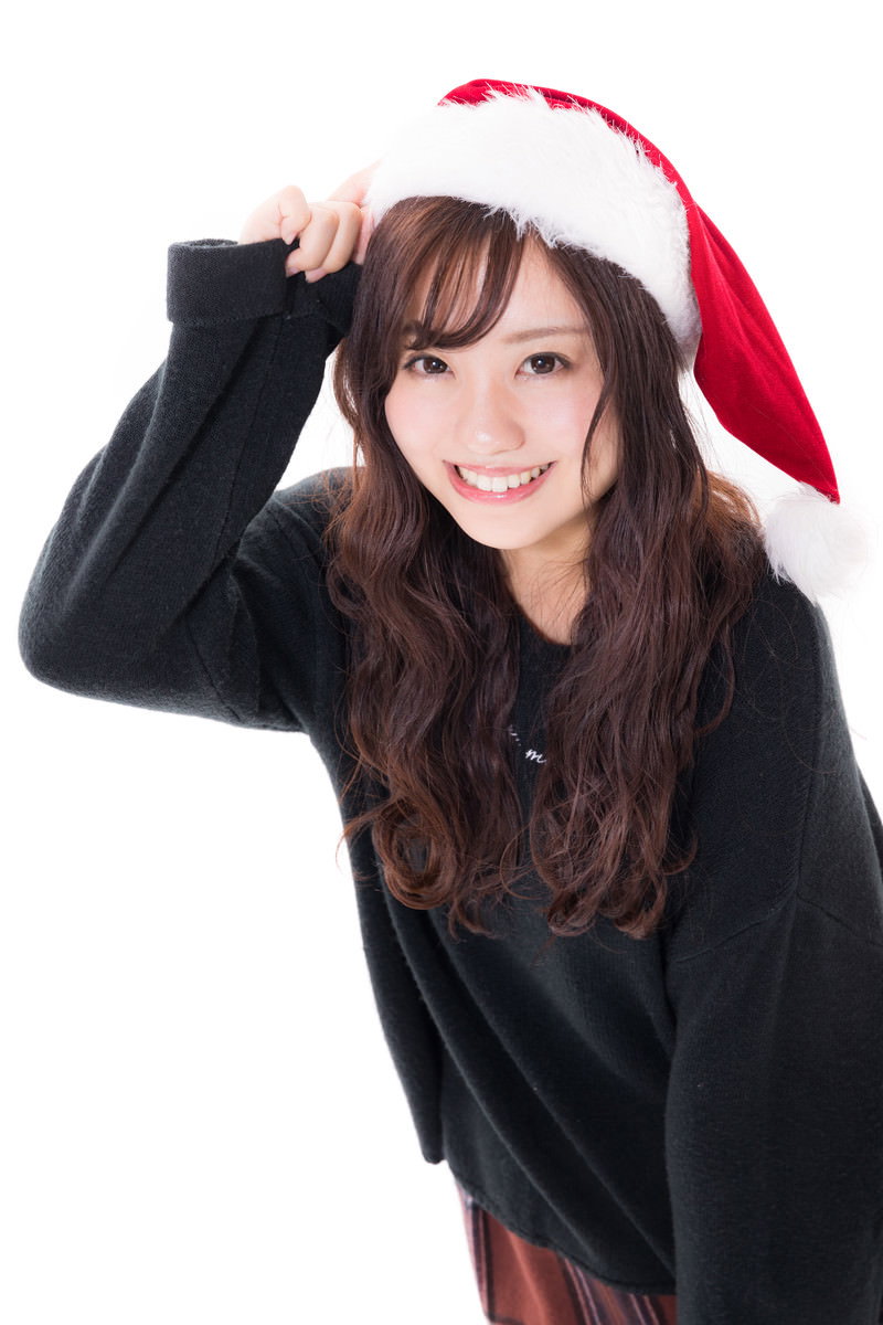 赤いサンタ帽をかぶり笑顔を見せる黒い服の女性［モデル：河村友歌］