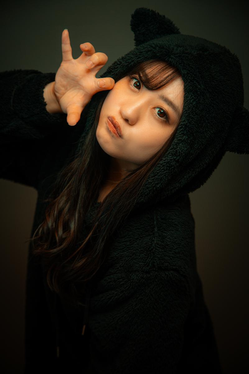 黒い猫耳フード付きのパジャマを着た女性がポーズを取っている［モデル：河村友歌］