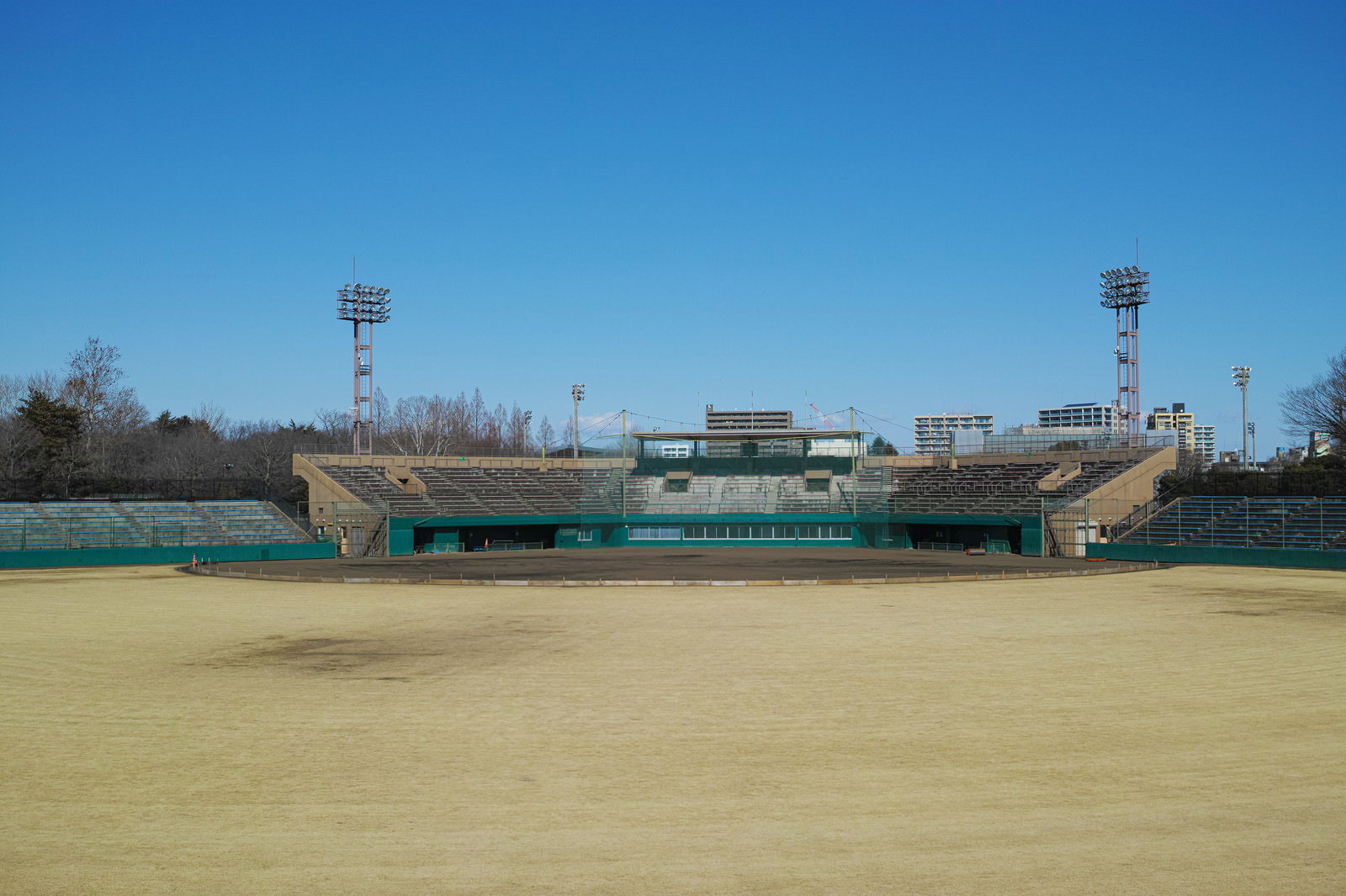 冬の無人野球場、枯れ芝のグラウンドとスタンド