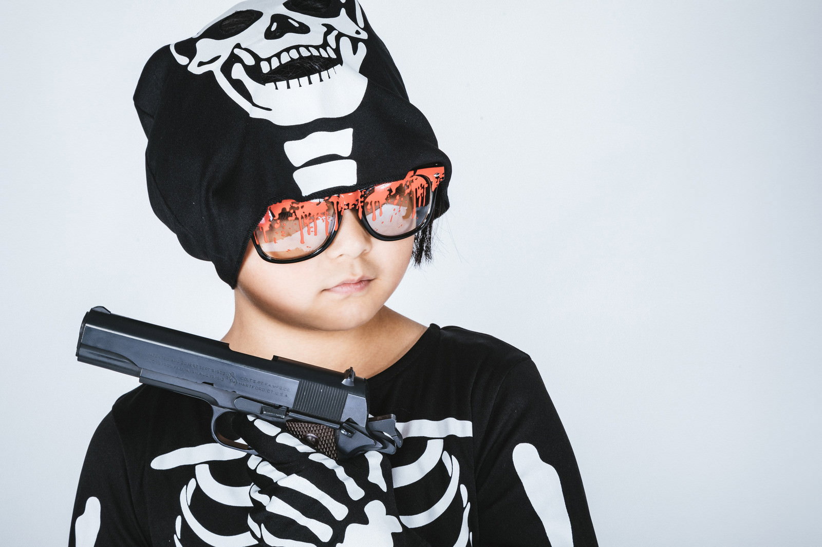 黒いスカルスーツを着て眼鏡をかけた男の子が拳銃を持つハロウィン仮装［モデル：ゆうき］