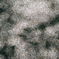 小石が埋まったコンクリート地面と影の舗装路テクスチャーの写真