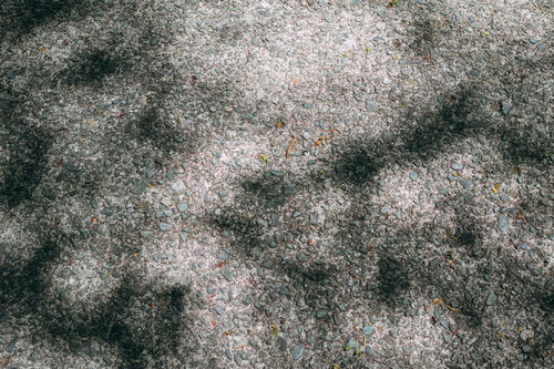 小石が埋まったコンクリート地面と影の舗装路テクスチャー