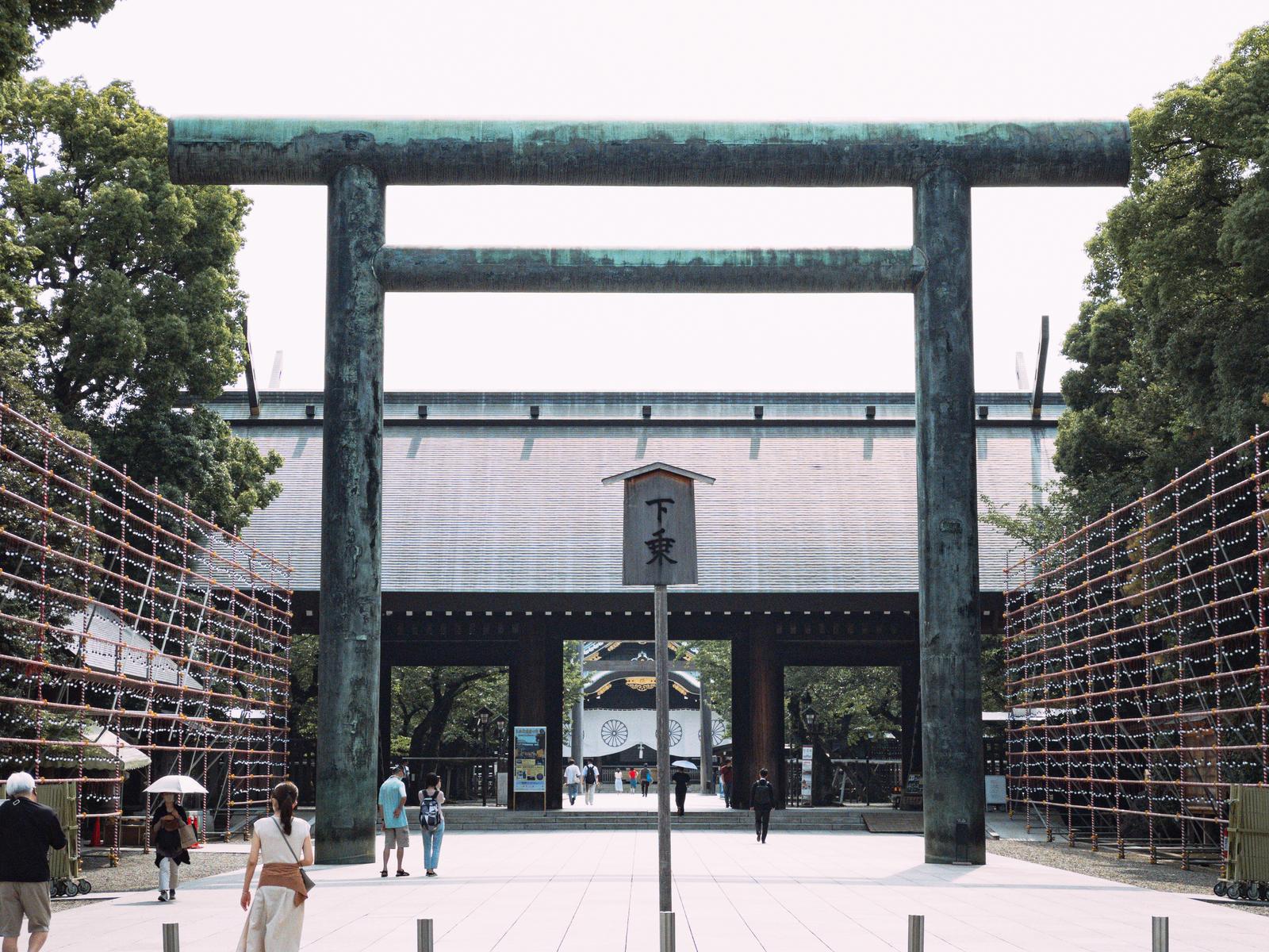 緑青に覆われた靖国神社の大鳥居と参拝客が歩む境内