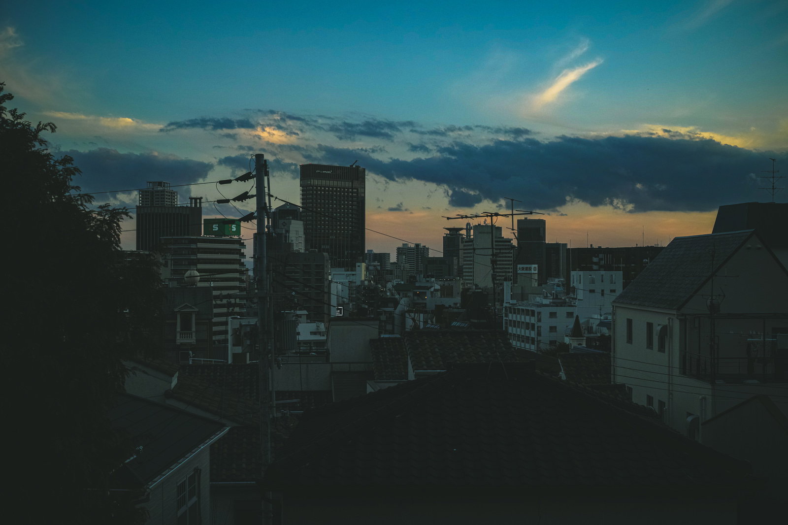 夕暮れ時のオレンジ色の空に浮かぶ建物の屋根のシルエット