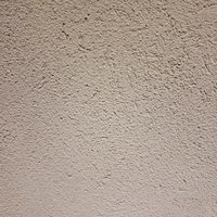 シミが浮かぶ白いモルタル壁のざらついたテクスチャーの写真