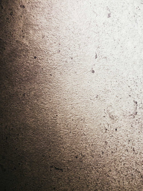 暗闇に浮かび上がる粗いコンクリート外壁のテクスチャー