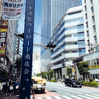 東池袋商店会の街並みと高層ビル、電線が張り巡らされた車道の写真