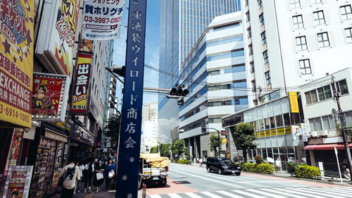 東池袋商店会の街並みと高層ビル、電線が張り巡らされた車道