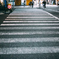 横断歩道の先で信号待ちする複数の歩行者たちの写真