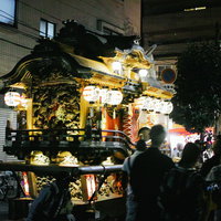 夏祭りで担がれる御輿と屋台、提灯の明かりの写真