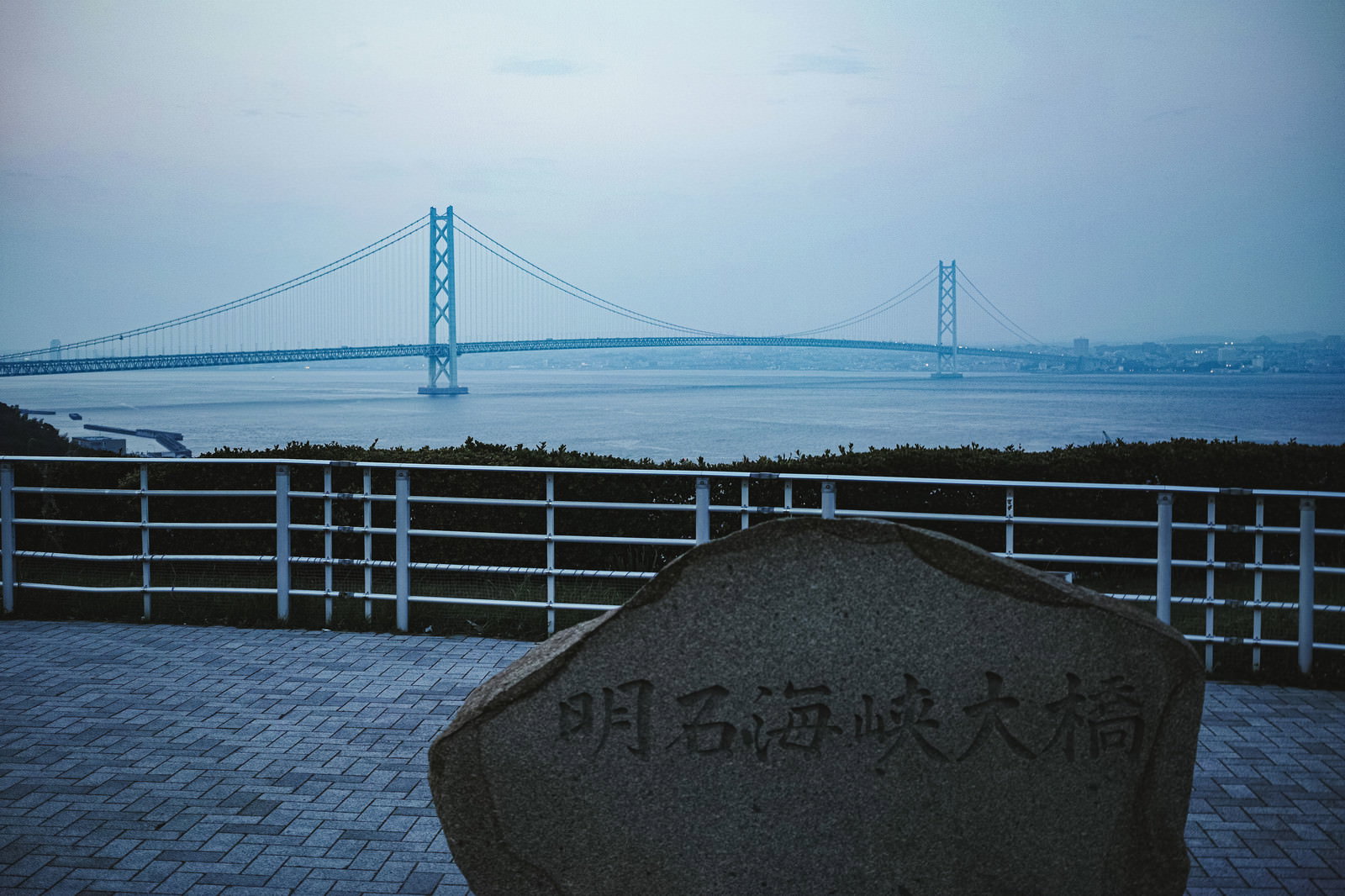 夕暮れの明石海峡大橋と手前の石碑を捉えた風景