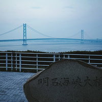 夕暮れ時の明石海峡大橋と展望台の石碑を見渡す風景の写真