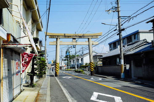 車道の中央に立つ八幡宮の黄色い鳥居と町並み