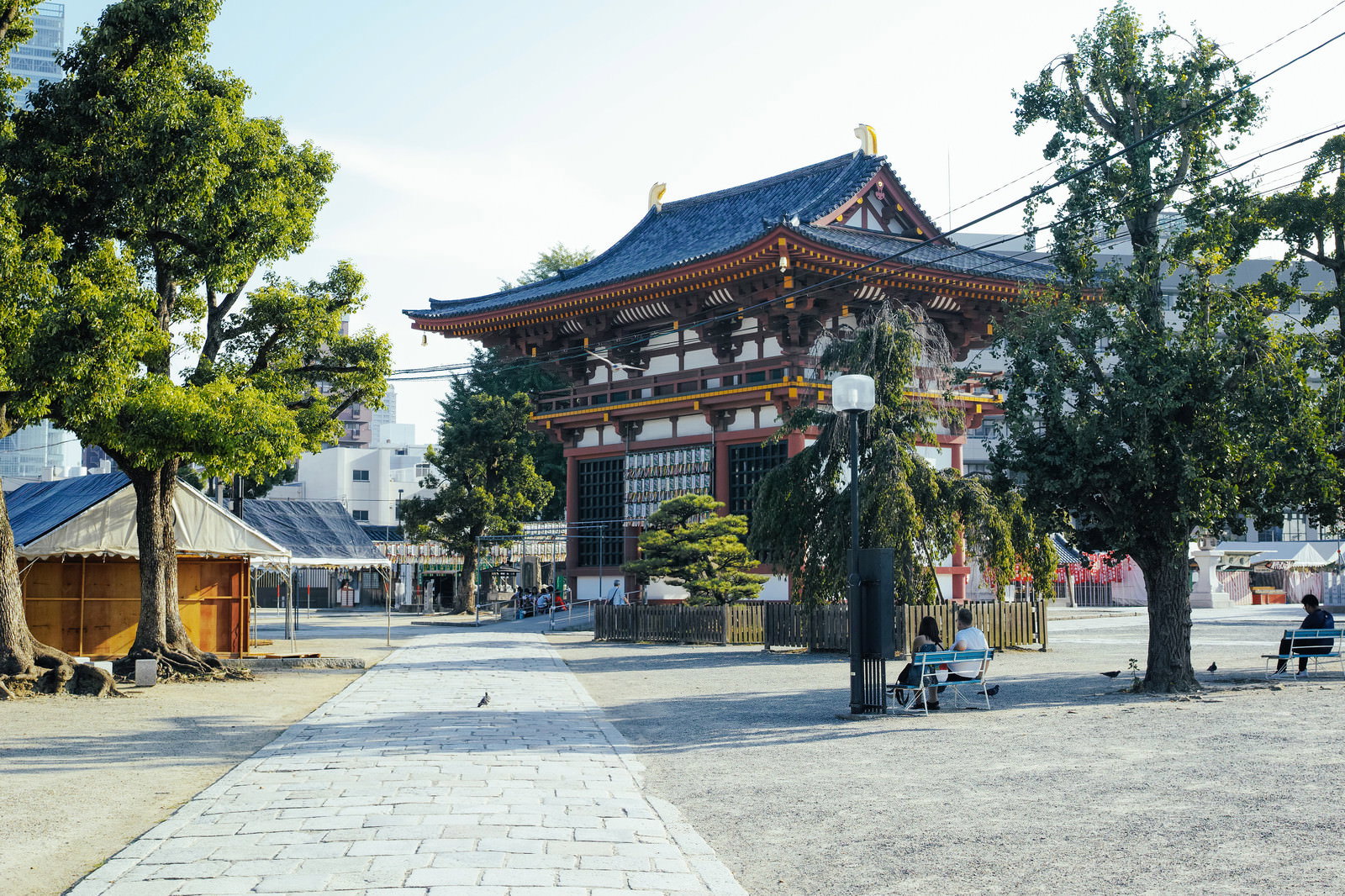 青い瓦屋根の四天王寺本堂と石畳の参道、緑豊かな境内の風景