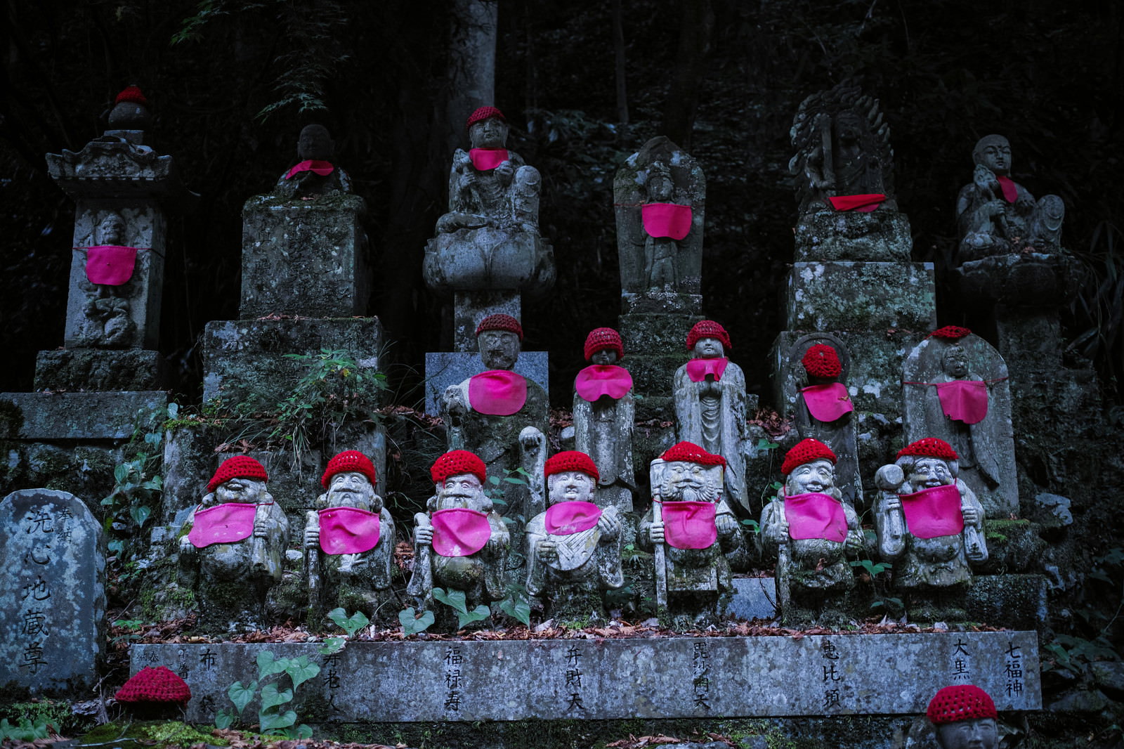 赤い帽子とよだれかけを身に着けた複数のお地蔵様が並ぶ様子