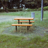 公園の芝生に設置された木製テーブルベンチセットの写真