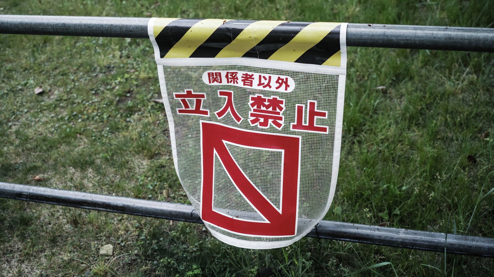 ガードレールに設置された赤い盾型の関係者以外立入禁止看板