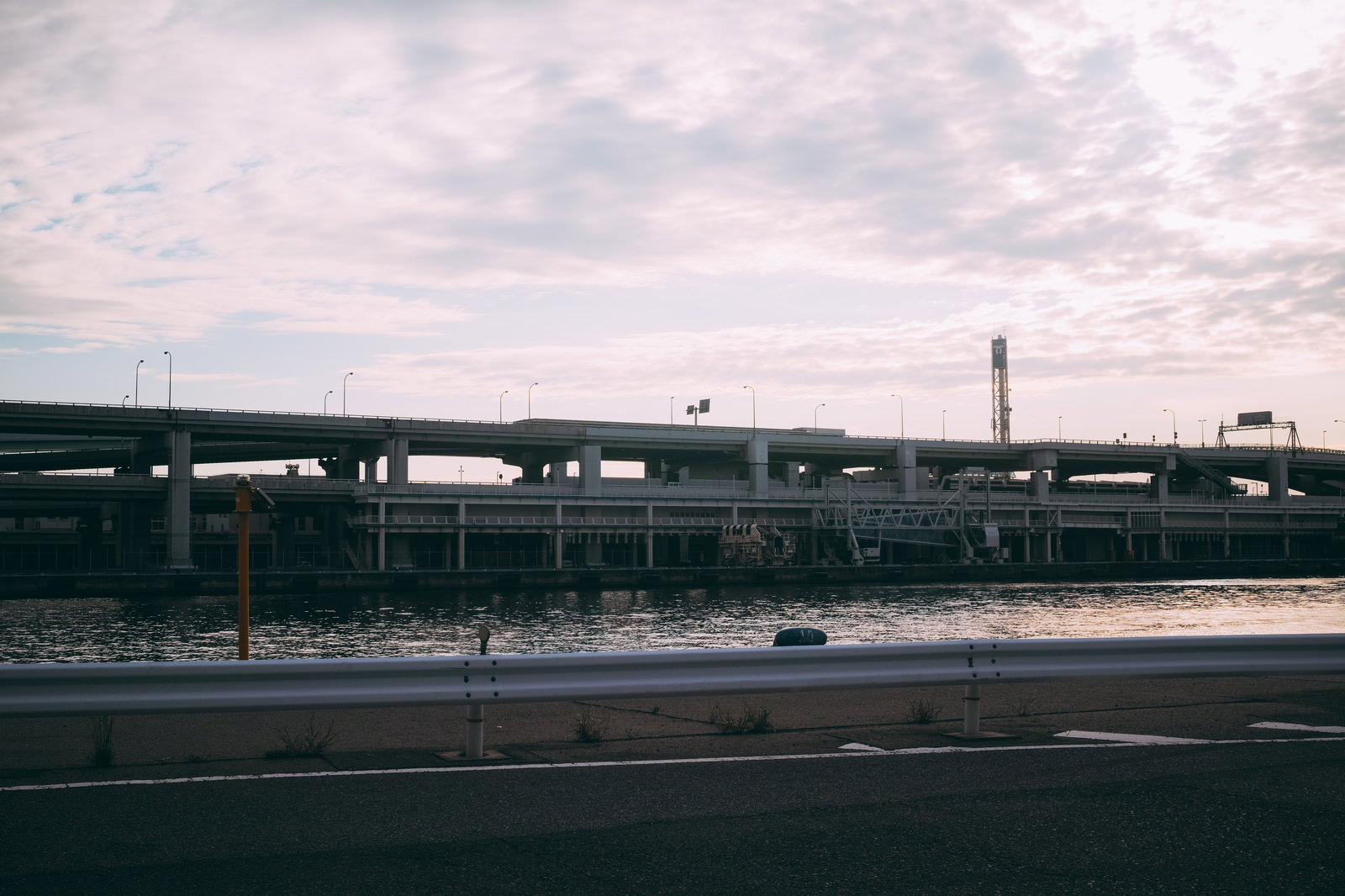 曇り空の下で光る水面と並行して延びる高速道路