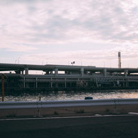 光る水面と高速道路のガードレール、夜間の橋梁インフラの写真