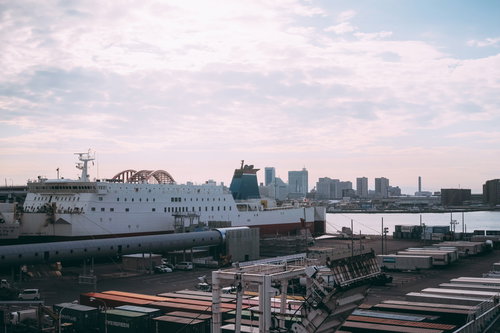 港の埠頭に停泊する大型船とコンテナ、遠くに見えるビル群