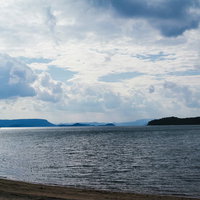 穏やかな海面に映る白い雲と遠い山並みの写真