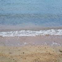波打ち際に残る白い泡と砂浜の夏のビーチ風景の写真
