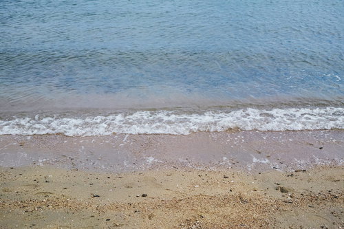 波打ち際に残る白い泡と砂浜の夏のビーチ風景
