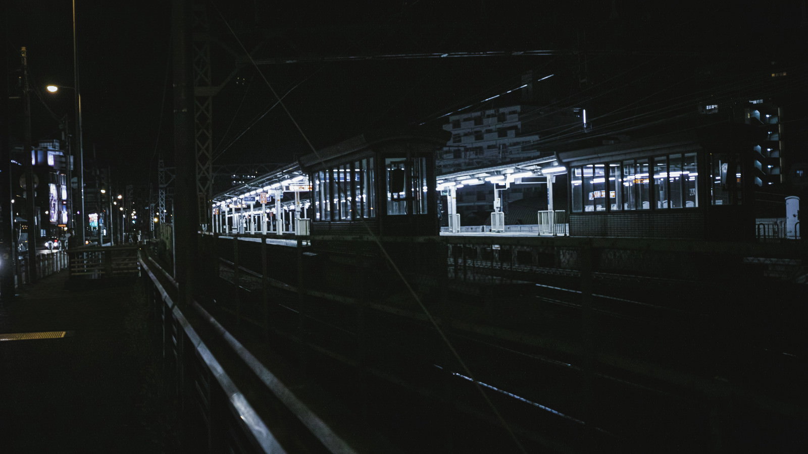 夜の駅ホームで白い照明がプラットフォームを照らす様子