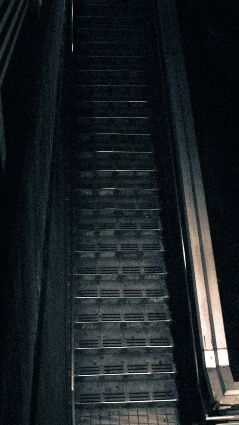 薄暗い夜のコンクリート階段を下から見上げた構図