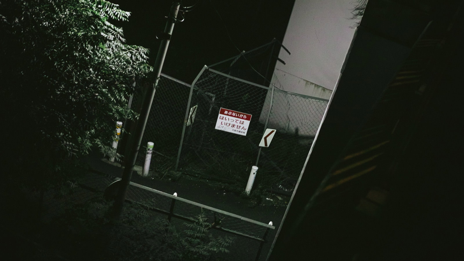 夜の暗闇の中で立ち入り禁止の警告板が取り付けられたフェンス