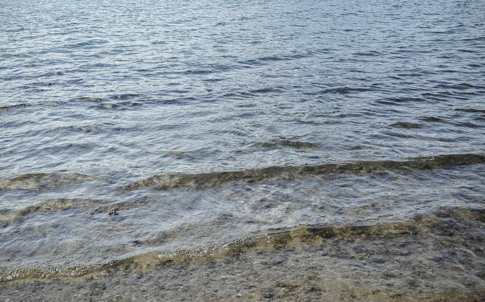 透明な海水で海底が透けて見える浅瀬の海面