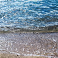 透明度の高い夏の海の波打ち際の白い砂浜と青い海の写真