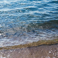 砂浜に寄せる波打ち際の波と砂浜のコントラストの写真