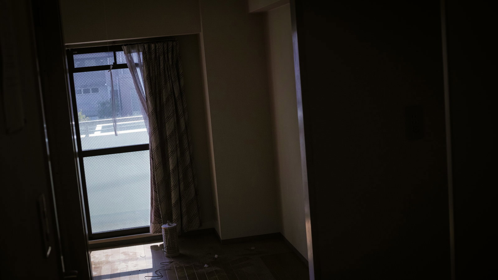 窓から光が差し込む薄暗いワンルームの室内