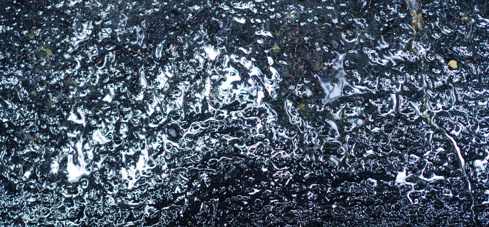 雨で濡れたアスファルトの路面に水滴が残っている様子