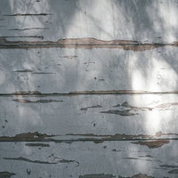 光に照らされる塗装が剥がれた壁の木目テクスチャーの写真