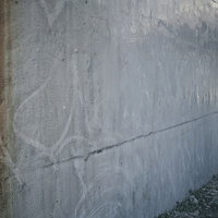 うっすらと落書き後の残るグレーのコンクリート壁の写真