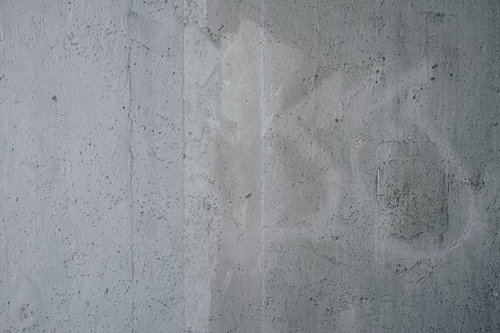 小さな穴が開いた落書き跡の残るコンクリート壁のテクスチャー