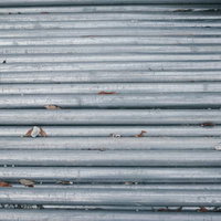 グレーの金属シャッターに小石や枯れ葉がはさまった様子の写真