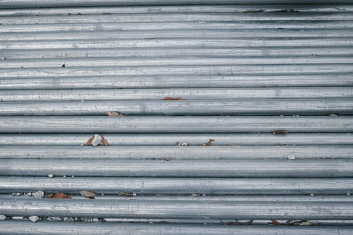 グレーの金属シャッターに小石や枯れ葉がはさまった様子